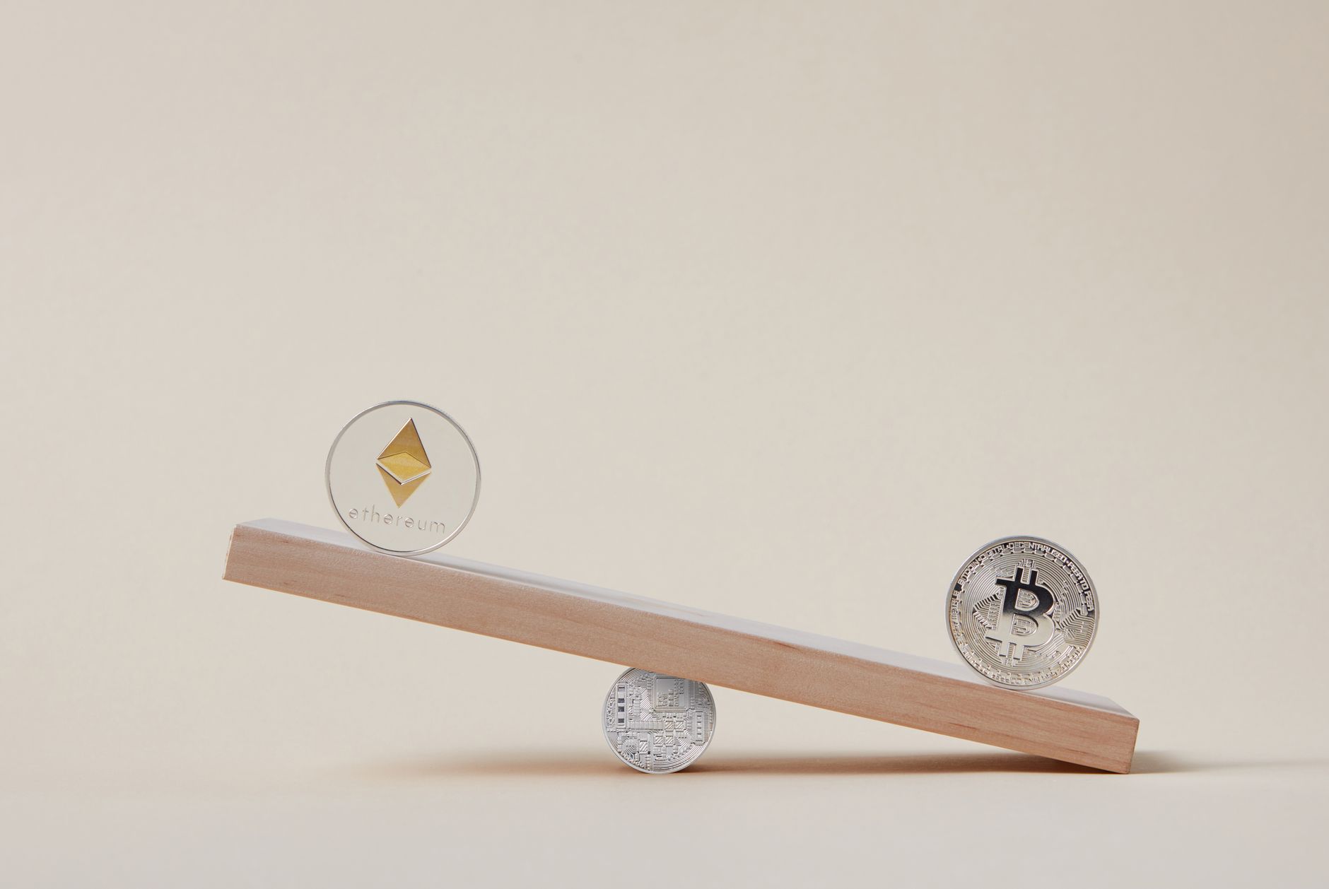 Ilustrasi: Minimalist image of Ethereum and Bitcoin coins balancing on a plank, symbolizing crypto market dynamics.