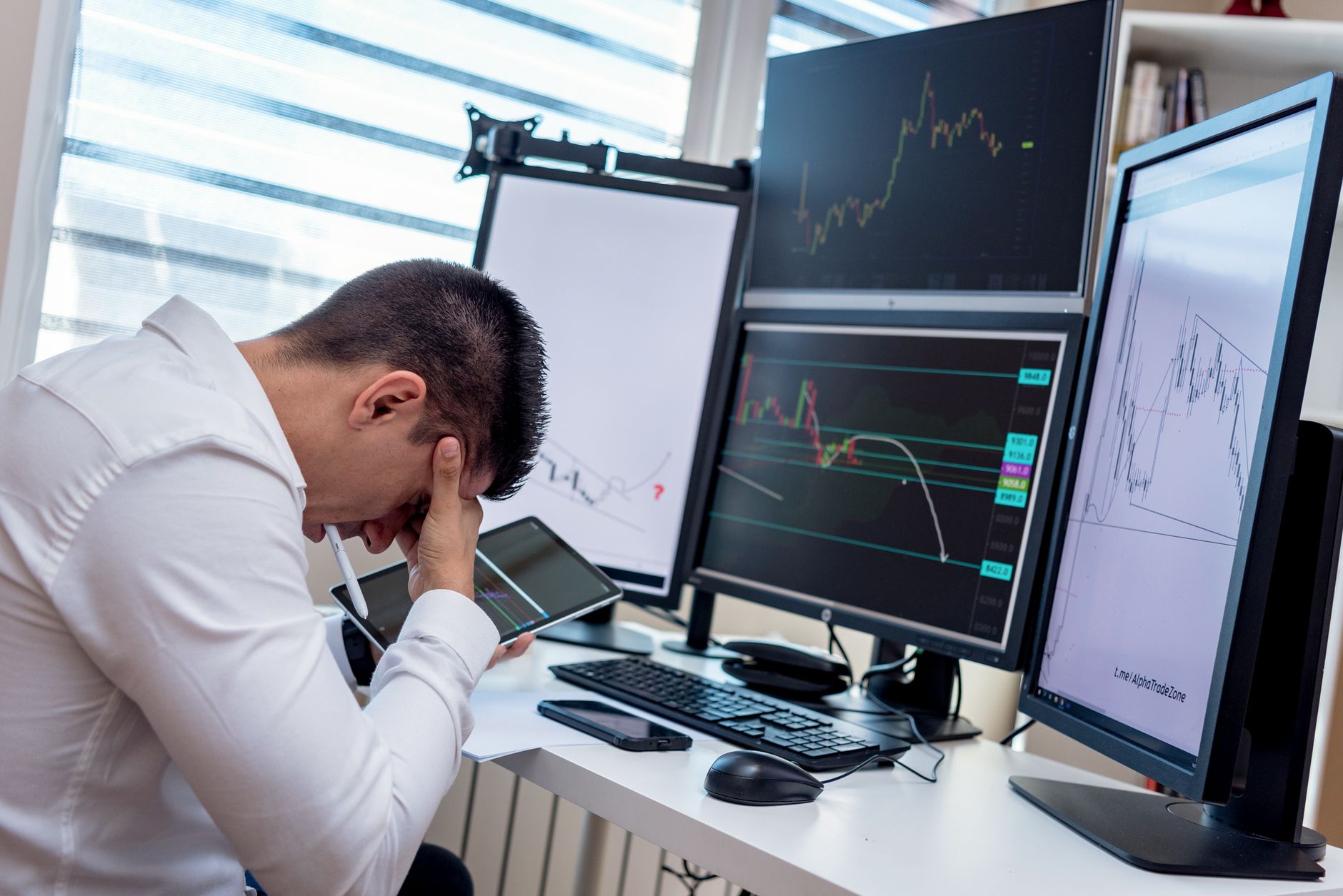 Ilustrasi: A stressed trader in an office setting analyzes market data on multiple monitors using a tablet.