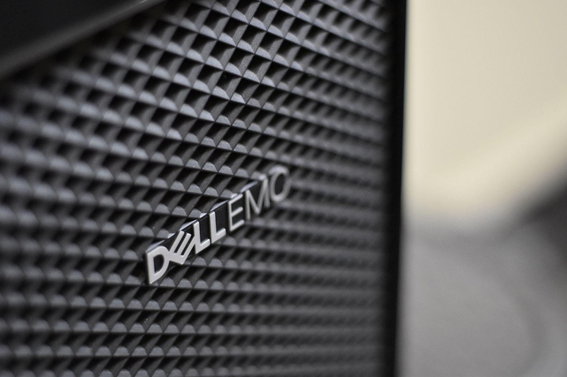 Ilustrasi: Detailed close-up of Dell EMC server logo on hardware grill with shallow focus and textured patterns.