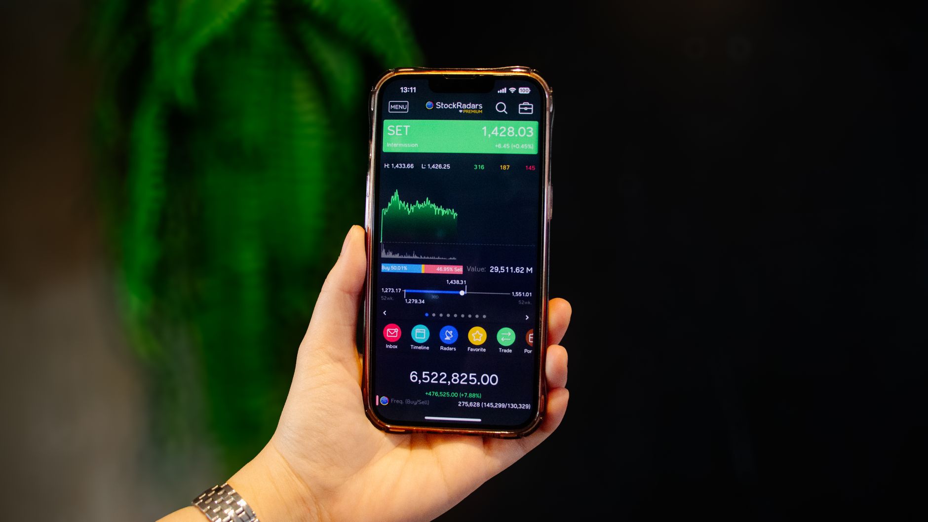 Ilustrasi: Close-up of a hand holding a smartphone displaying a stock trading app with real-time data.