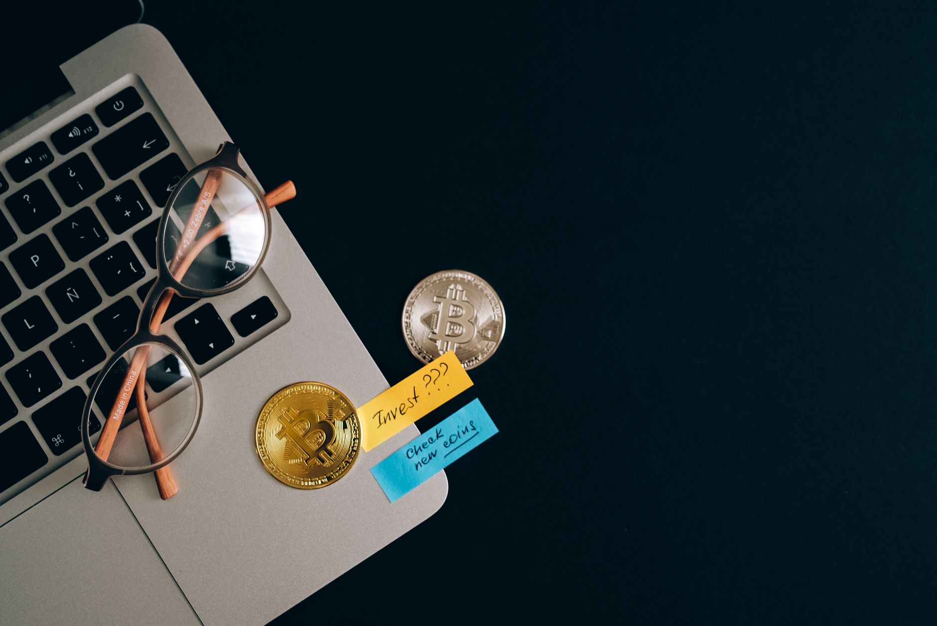 Ilustrasi: Laptop, bitcoins, and notes on a desk representing cryptocurrency investment concept.