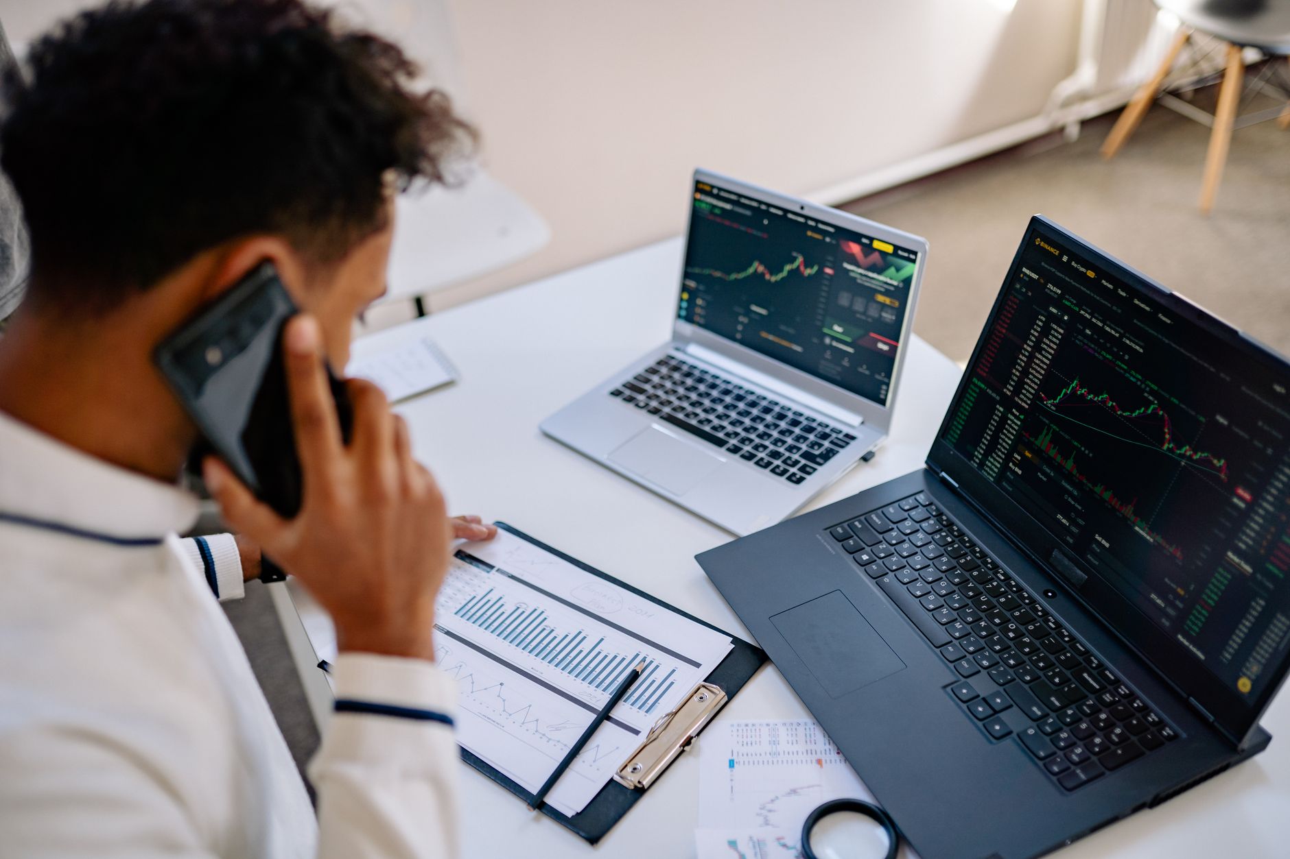Ilustrasi: Man analyzing stock market charts on laptops while talking on a cellphone.