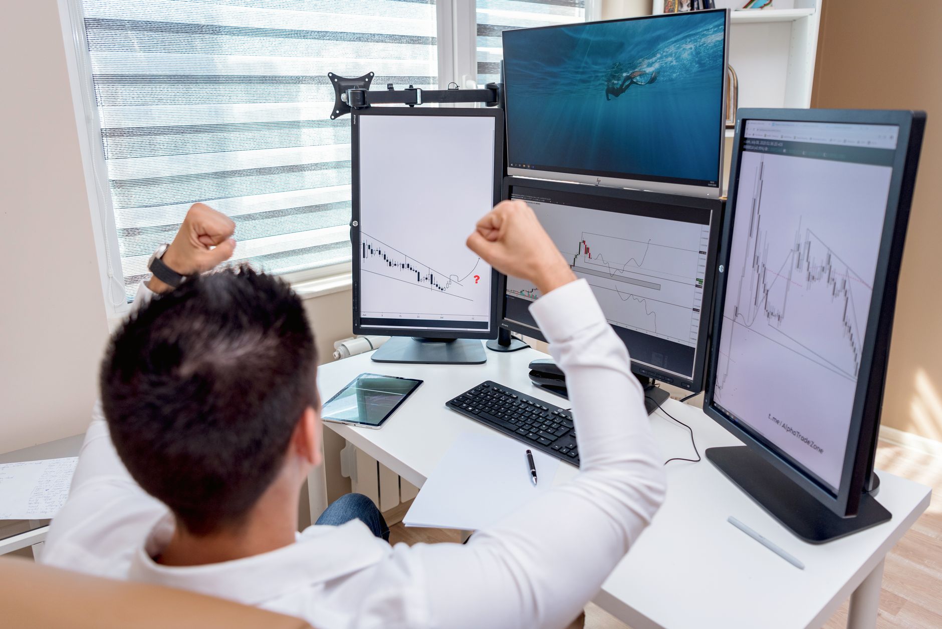 Ilustrasi: A man celebrates in front of multiple computer monitors displaying stock market graphs, indicating trading success.