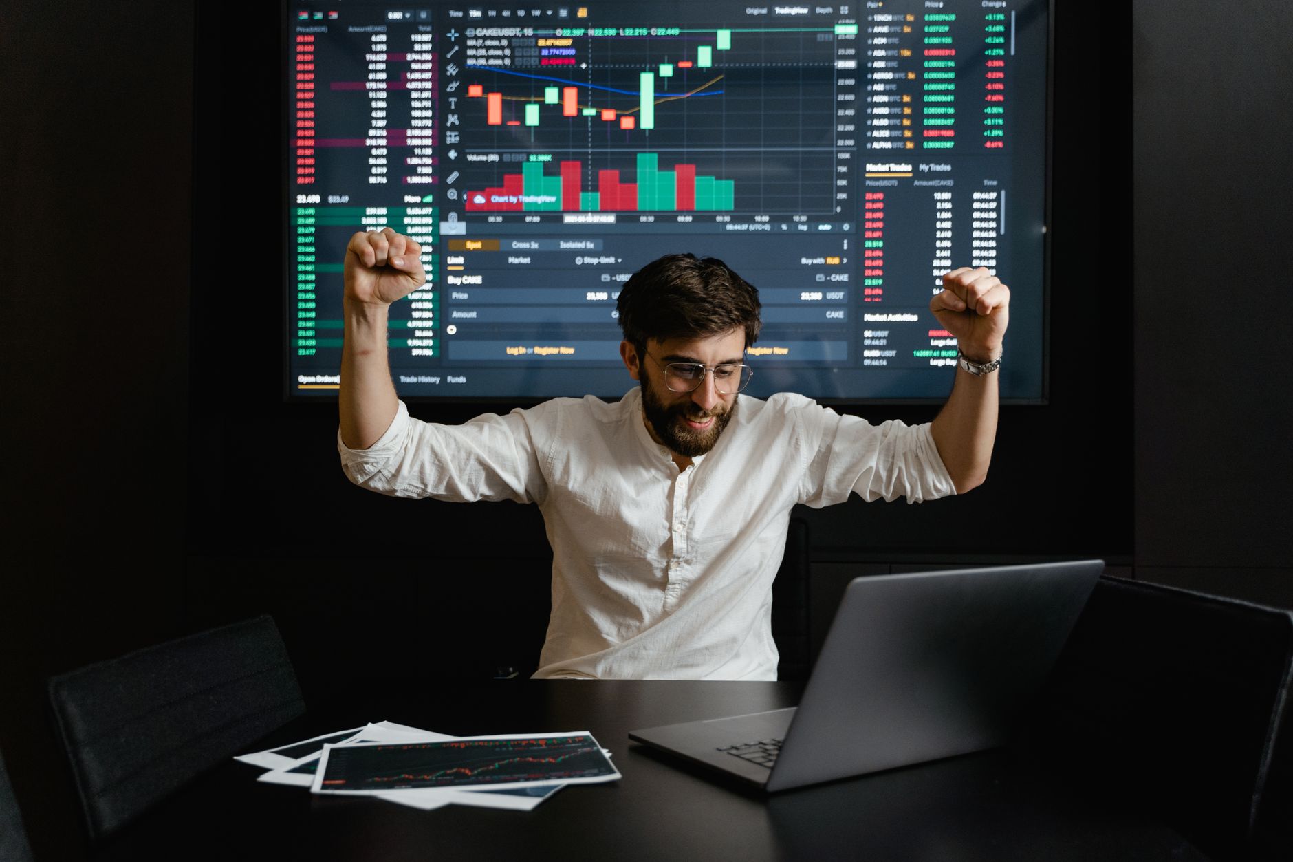 Ilustrasi: Businessman celebrates stock market success with hands raised in excitement at a trading desk.
