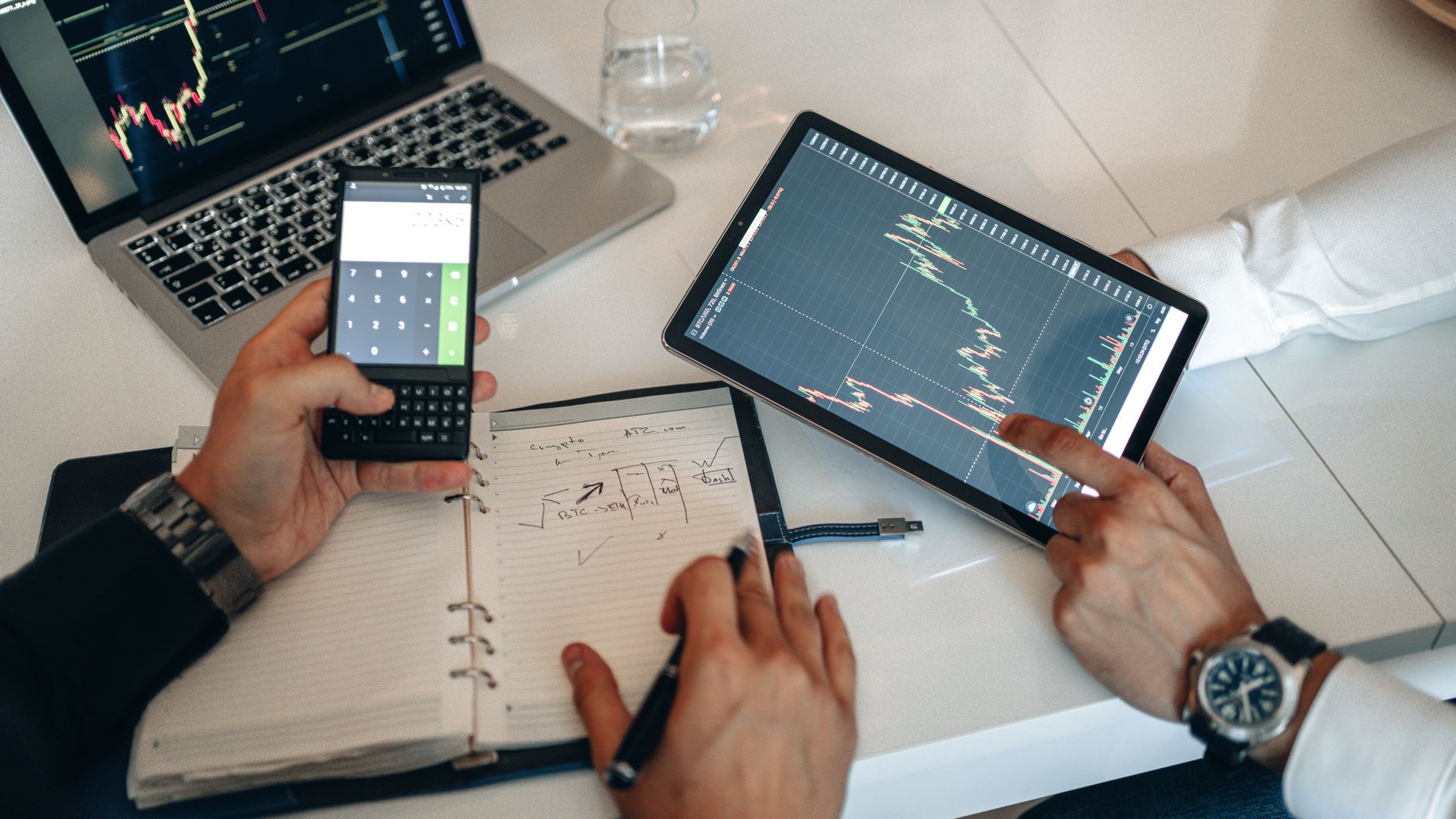 Ilustrasi: Business professionals analyzing charts on digital devices during a meeting.