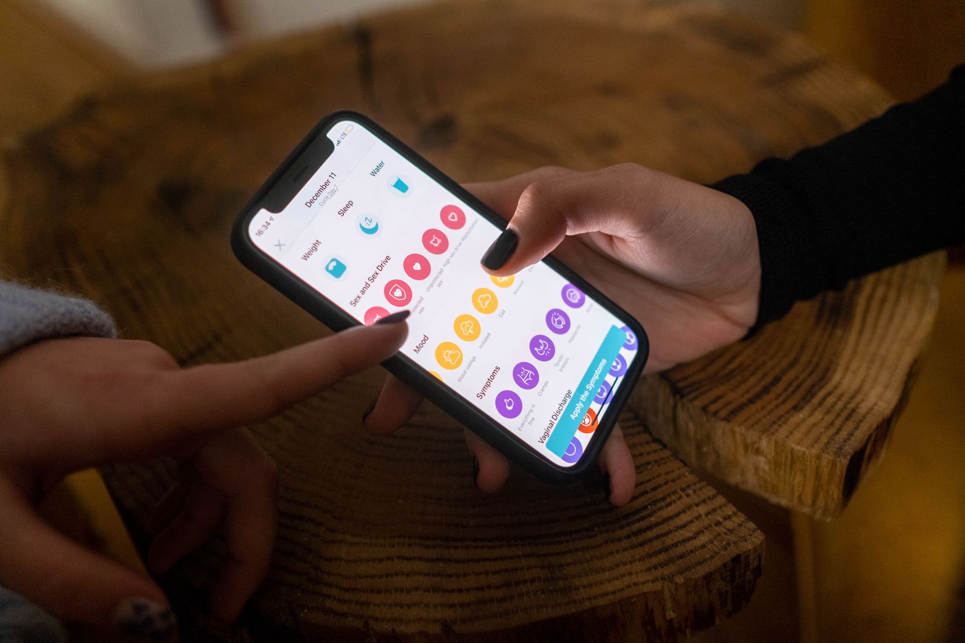 Ilustrasi: Close-up of hands using a fertility tracking app on a smartphone indoors.