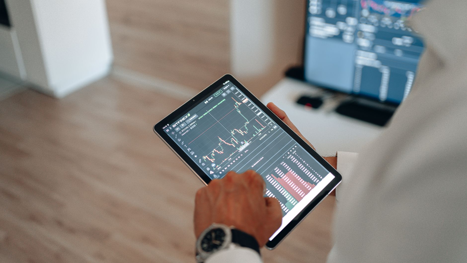 Ilustrasi: Close-up of hands using a tablet for online trading and market analysis.