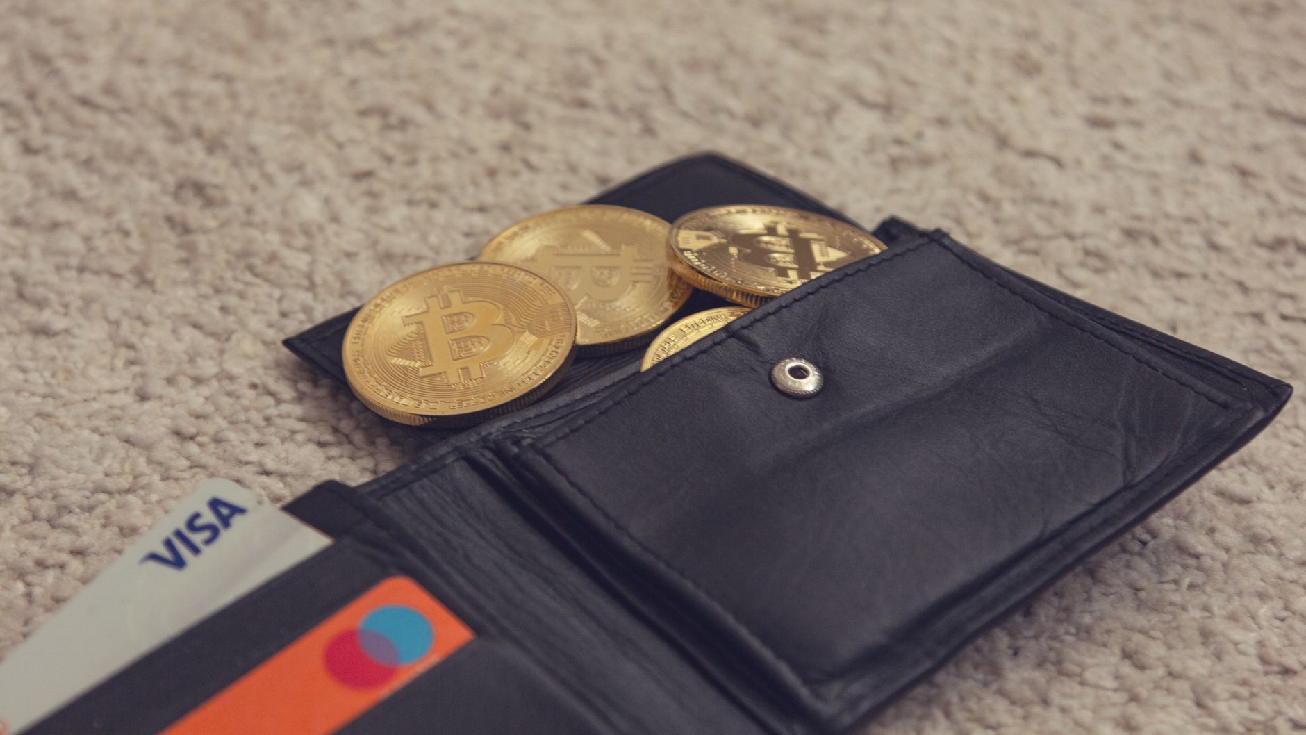 Ilustrasi: Close-up of bitcoins and credit cards inside a leather wallet, representing digital currency and finance.