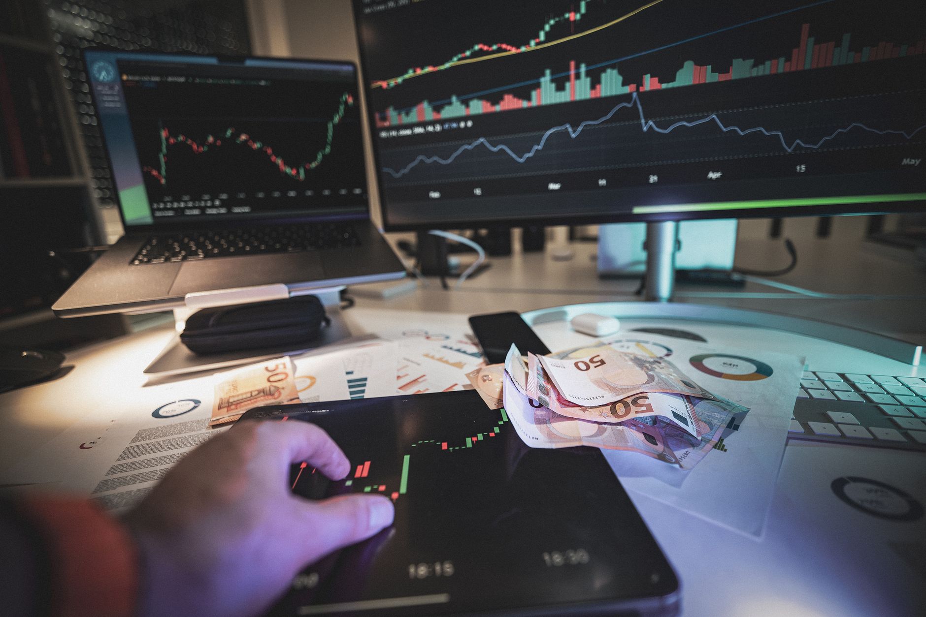 Ilustrasi: A modern trading desk with screens showing market charts and euro notes, capturing a trading atmosphere.