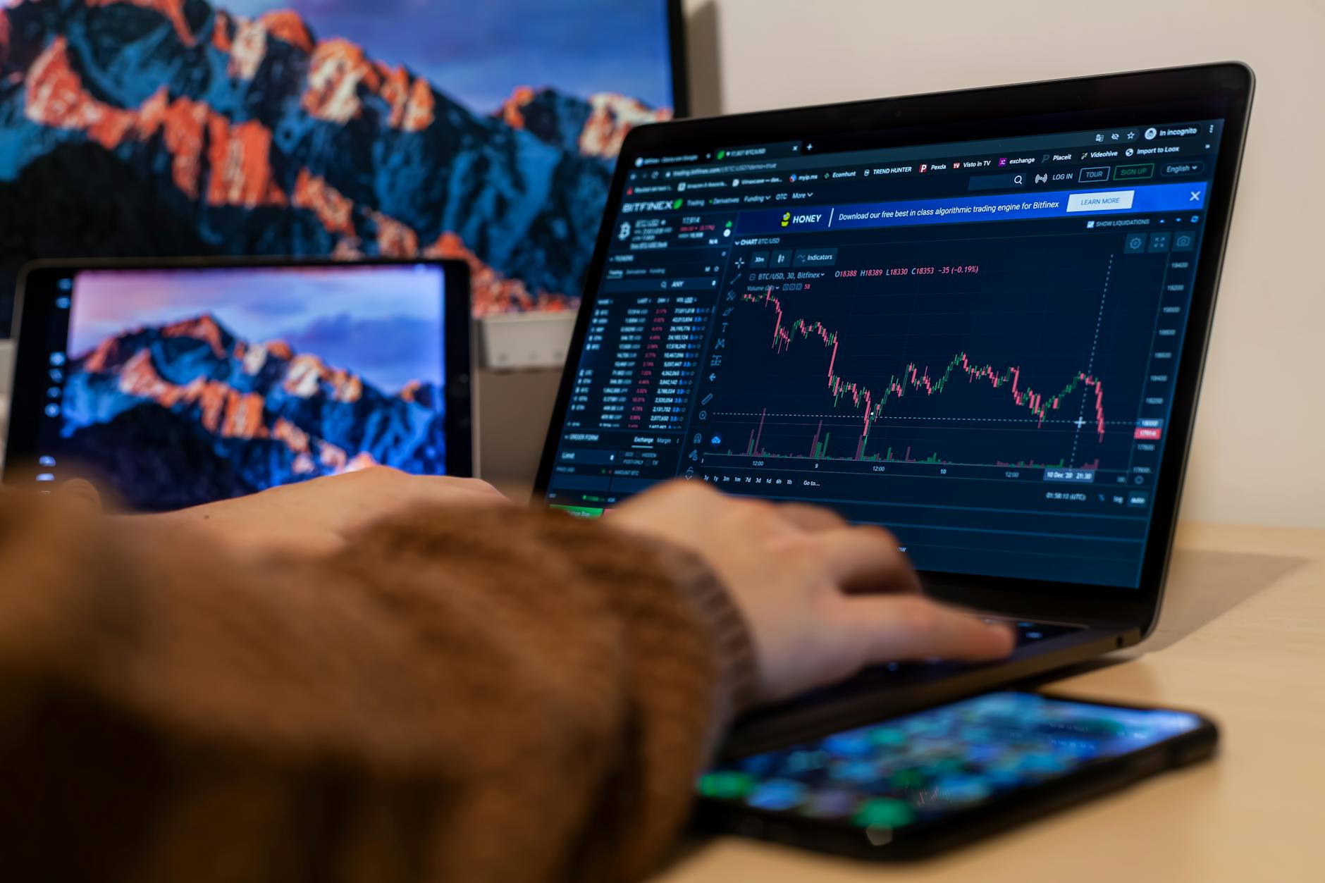 Ilustrasi: Close-up of hands typing on a laptop with stock charts displayed, analyzing financial data.