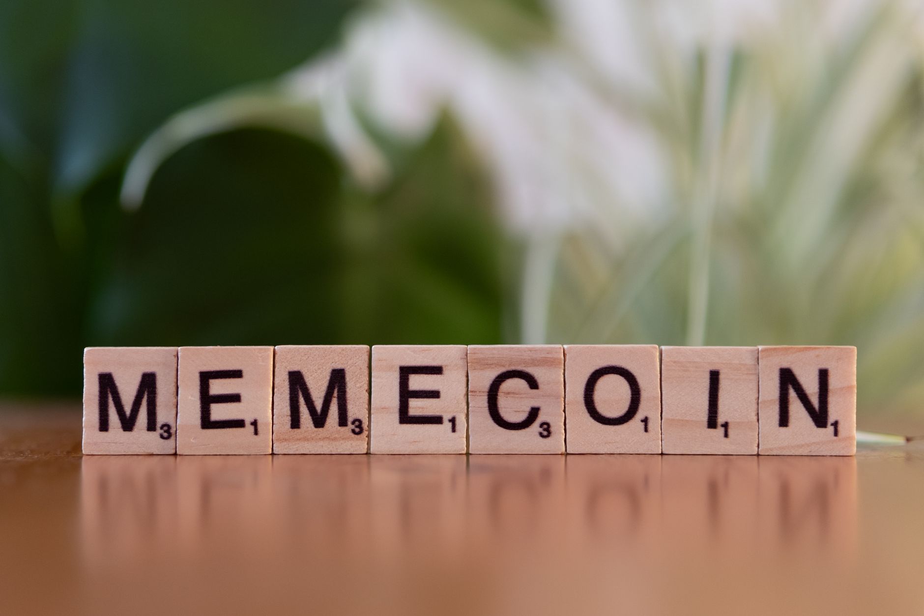 Ilustrasi: Wooden tiles spelling 'Memecoin' on a blurred background.