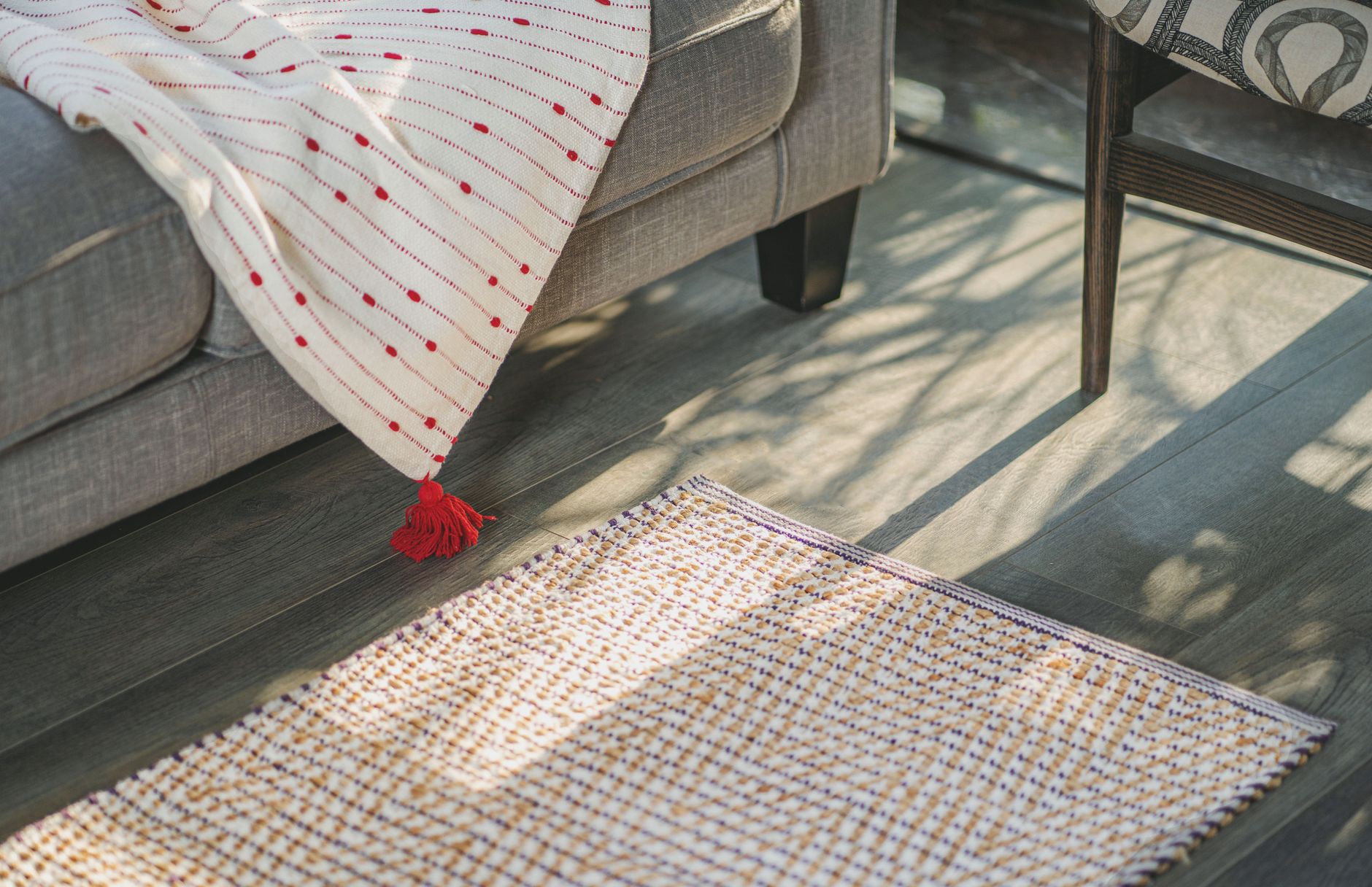 Ilustrasi: Bright living room featuring a textured rug and a decorative throw blanket on a gray sofa.