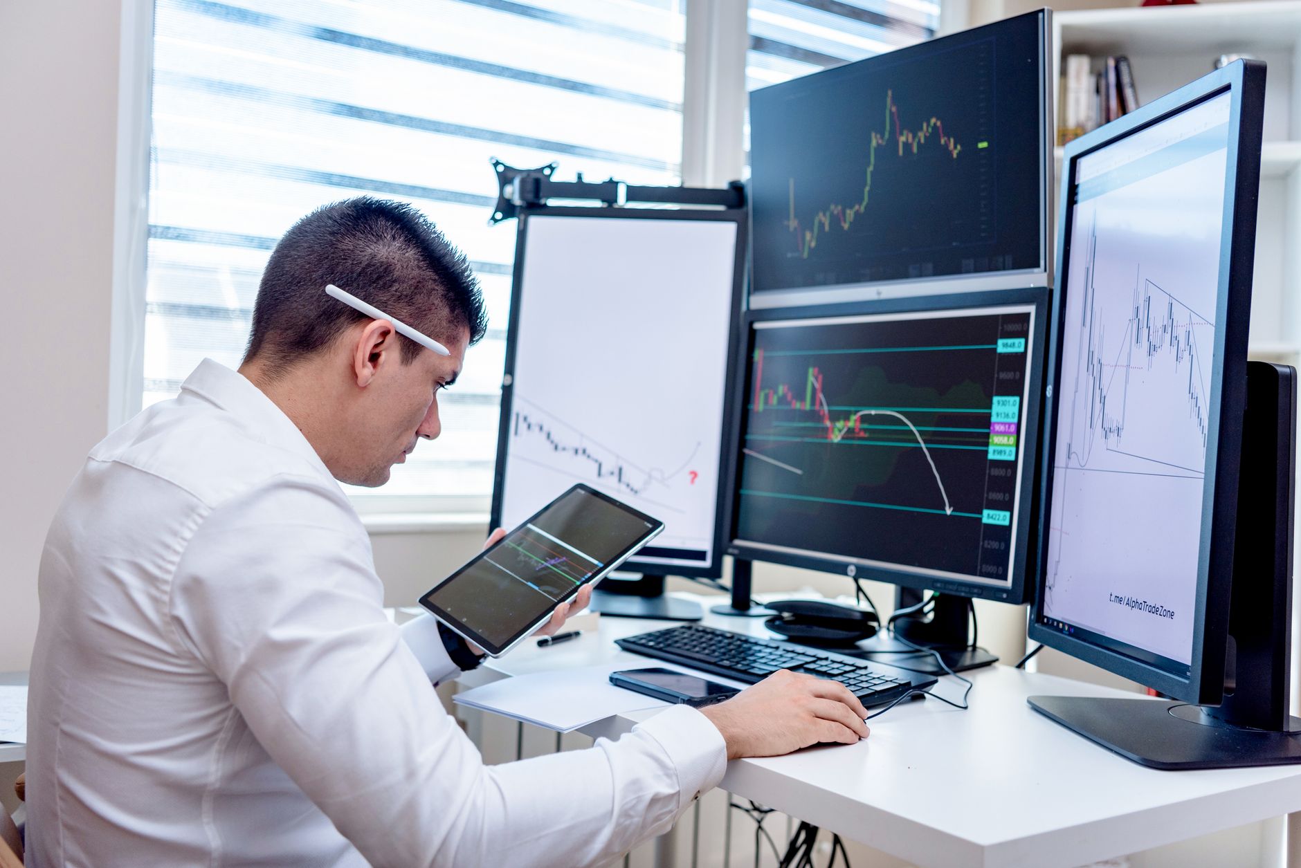 Ilustrasi: Professional analyzing stock market graphs on multiple monitors at work desk.
