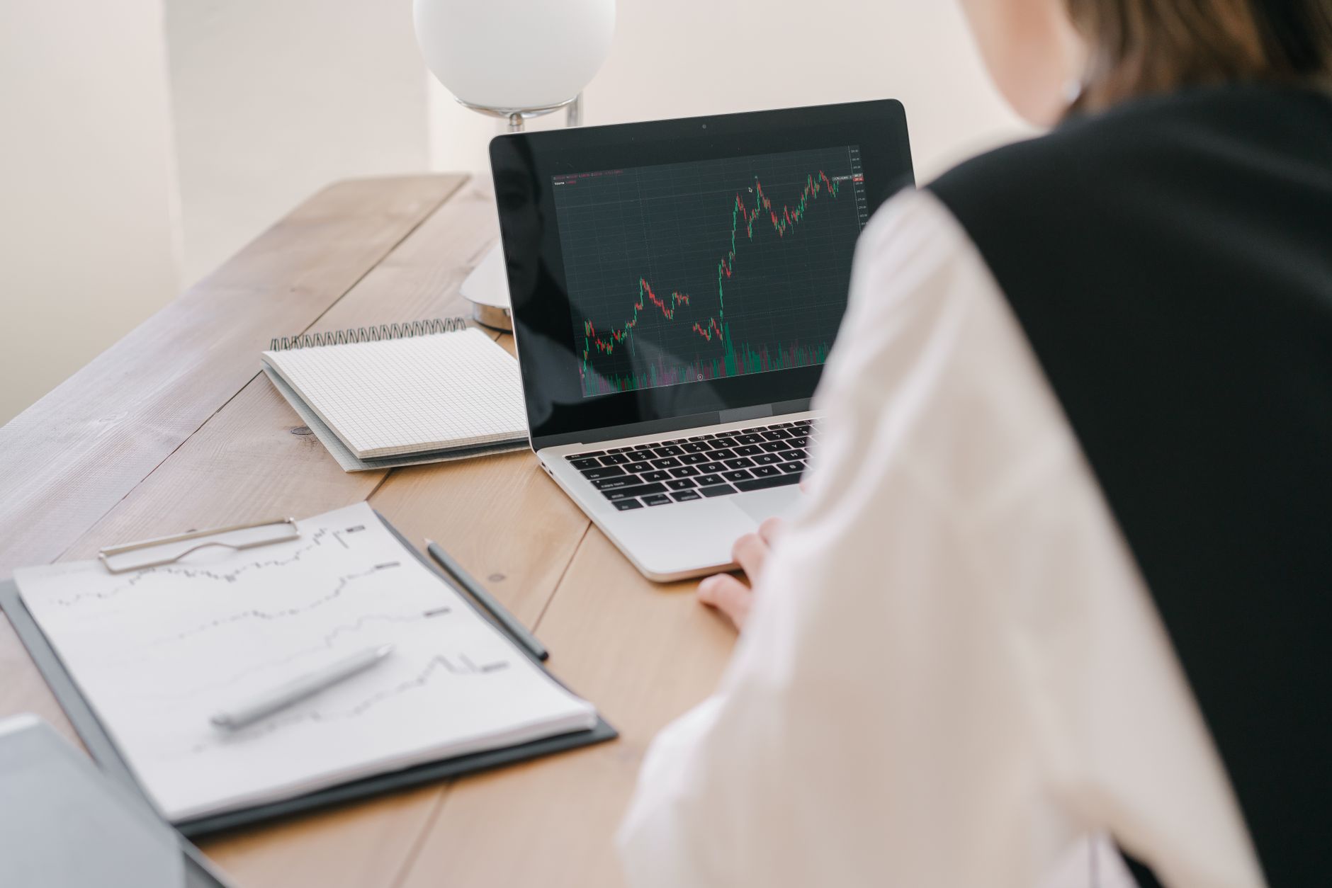 Ilustrasi: Business professional analyzing stock market trends on a laptop inside an office setting.