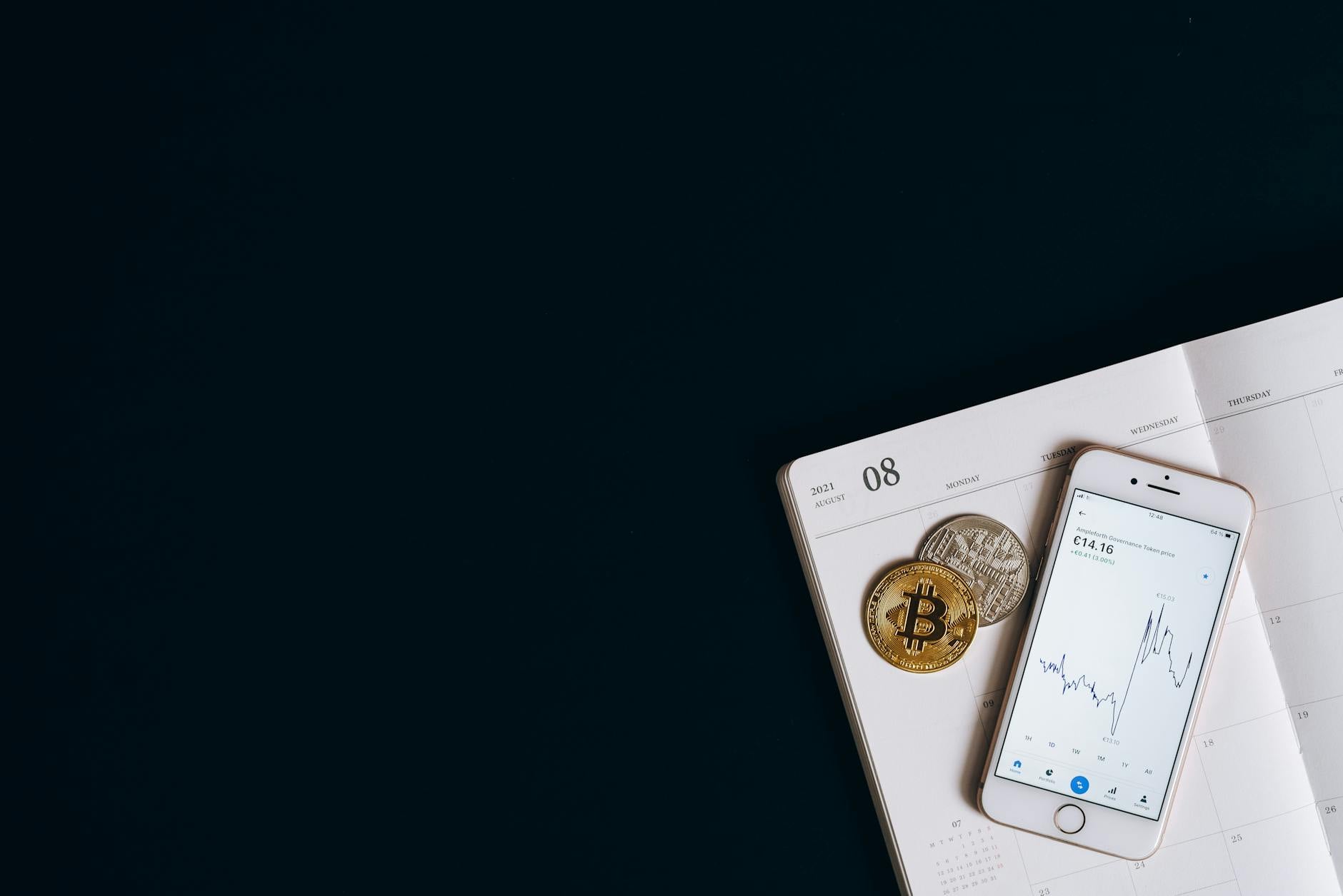 Ilustrasi: Smartphone displaying cryptocurrency data next to Bitcoin on a calendar offers finance and technology insights.